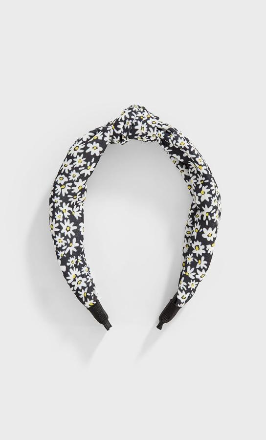 Con fondo negro y un bonito estampado de margaritas, esta diadema con nudo superior es de Stradivarius y tiene un precio de 5,99 euros.