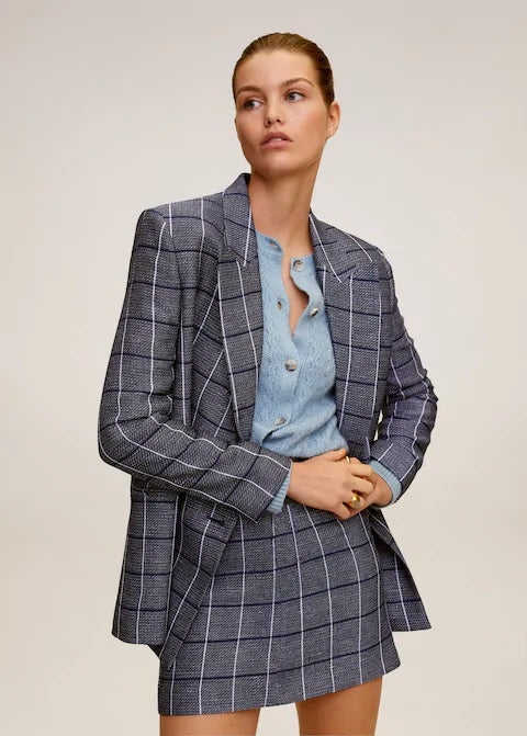 Pero también por los estampados de cuadros con esta americana de lino a juego con la falda mini que completa este traje de verano. (39,99 euros).