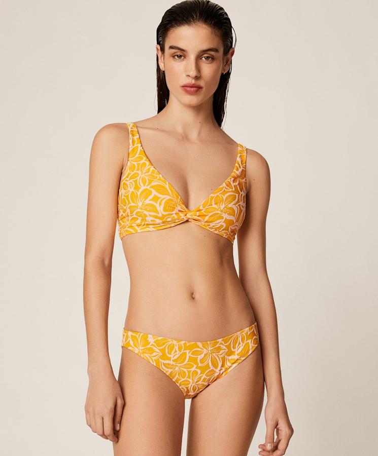 En color amarillo con detalles de flor, este bikini de sujetador (19,99 euros) halter con copa extraíble cuenta con tirantes ajustables con nudo trasero. A juego encontramos la braguita (12,99 euros) brasileña.