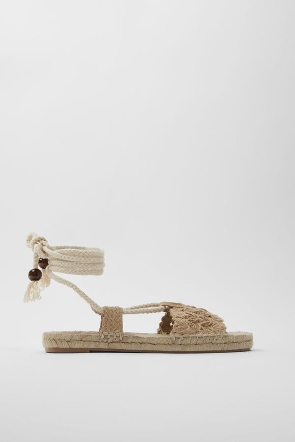 Zara nos propone esta alpargata de yute de color natural y cierre mediante atado alrededor del tobillo con cuerda con detalle de bolas de madera. Tiene un precio de 39,95 euros.