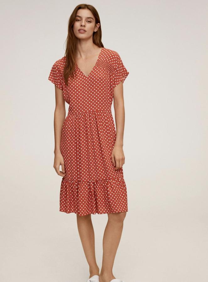Mango nos propone este vestido de manga corta y escote de pico con estampado de lunares en rojo y blanco. Con volante en el bajo y ceñido en la cintura, tiene un precio de 25,99 euros.