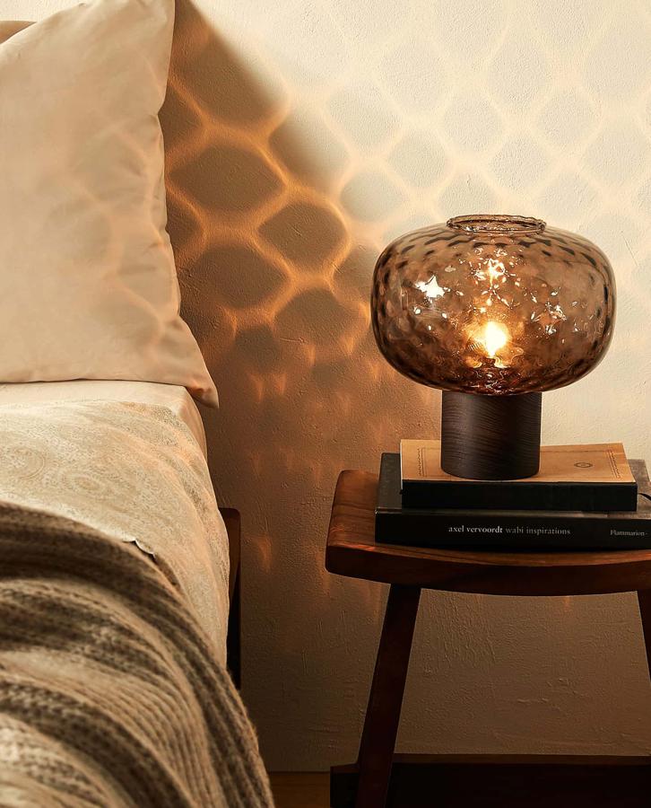 Esta lámpara con base de madera y pantalla de vidrio en gris oscuro es ideal para dar una cálida luz. Es de Zara Home y tiene un precio de 49,99 euros.