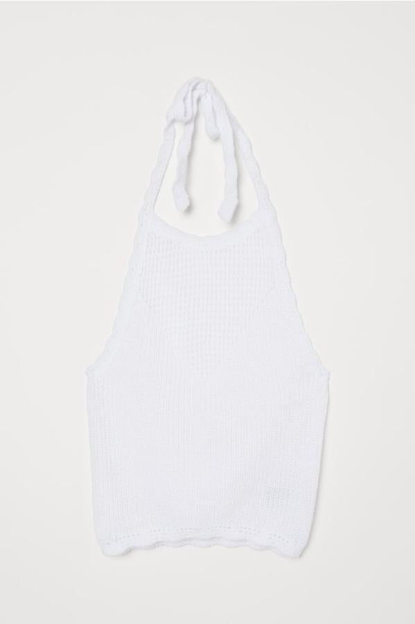 En punto de algodón, con tiras de anudar en el cuello y la parte superior y el bajo festoneados, este bonito top en color blanco es de H&M. Tiene un precio de 14,99 euros y está disponible entre las tallas XXS y XL.