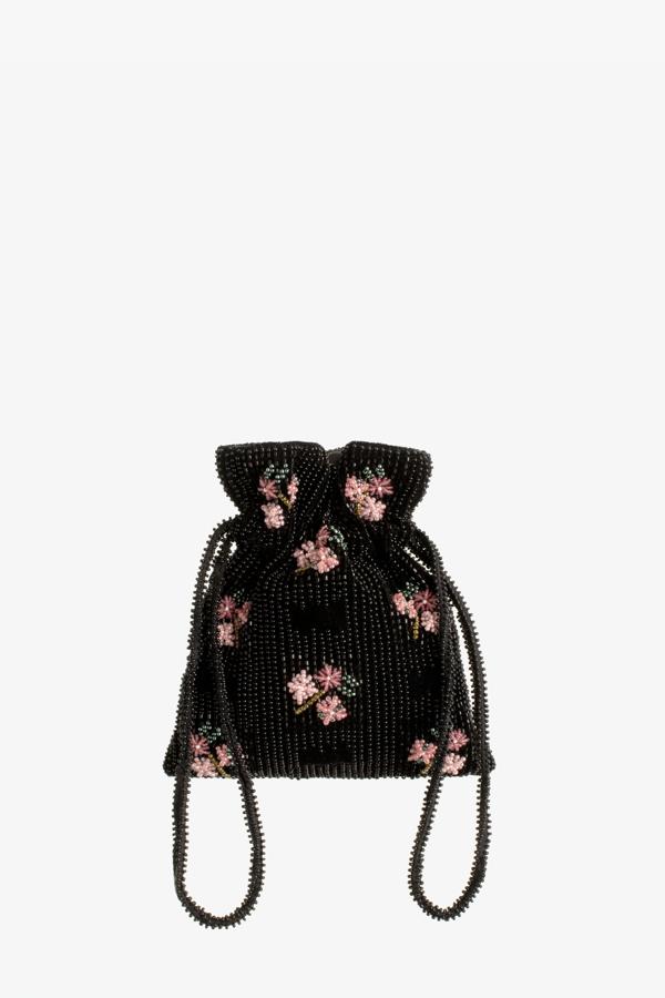 El formato mini saco de Zara tiene un bonito diseó de mano en color negro con detalle de aplicación de abalorios y flores en color rosa. Con cierre de cordones ajustables, es de edición limitada y cuesta 29,95 euros.