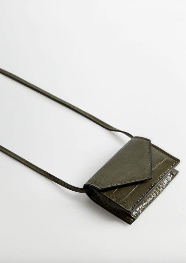 Con asa larga y cierre de clip metálico, este bolso mini de Mango con efecto cocodrilo en color verde tiene un precio de 9,99 euros.