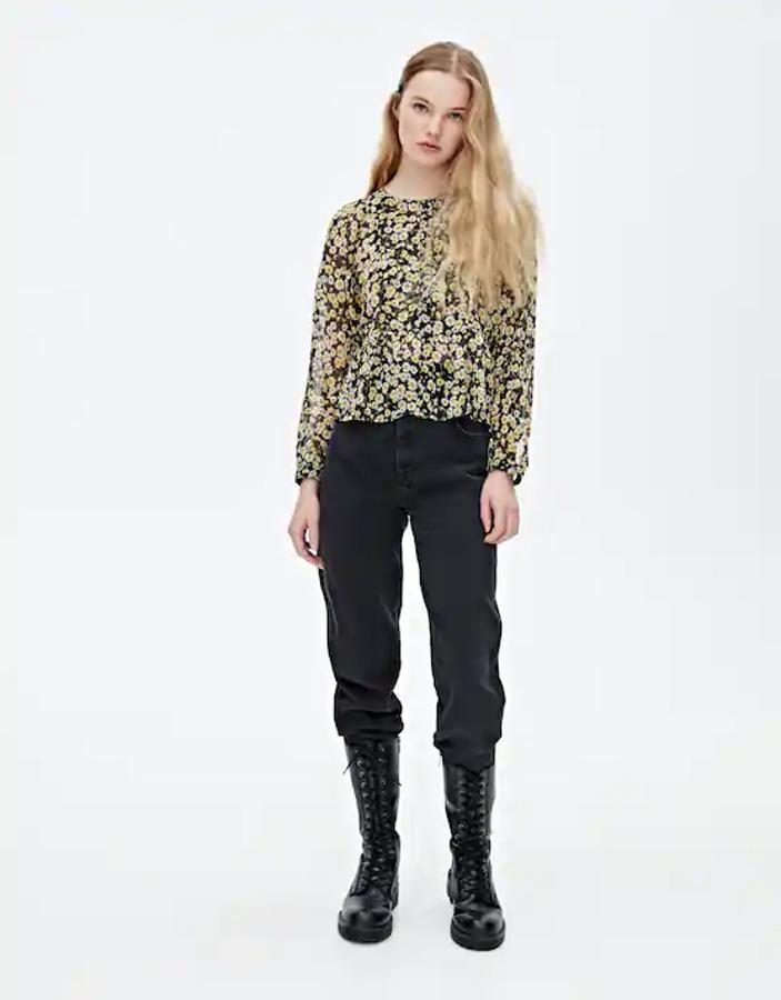 De color negro, con estampado de margaritas en contraste y detalle de volantes en el bajo, esta camisa de Pull&Bear tiene el cuello redondo y las mangas largas. De 19,99 euros ha pasado a costar 9,99 euros y está disponible entre las tallas XS y L.