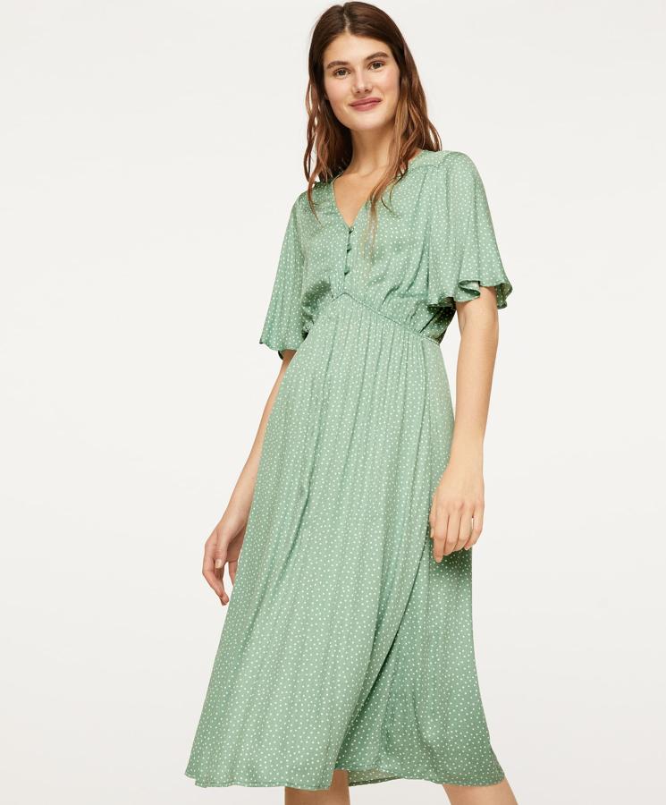 De manga corta con volantes y escote de pico con botonadura central, este vestido en color verde con pequeños topitos cuenta con corte a la cintura y tiene un precio de 25,99 euros.