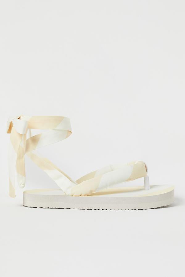 Sandalias con aire oriental, con tiras de raso en beige y blanco, de la colección de verano Studio de H&M (39,99 euros). Han tenido tanto éxito que ya se han agotado.