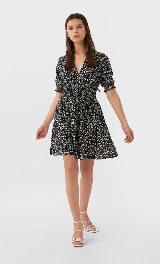 Escote de pico y manga corta abullonada con goma en la cintura y estampado en colores negros y blancos para este bonito vestido de Stradivarius con cierre en la espalda con lazada a tono. Tiene un precio de 25,99 euros y está disponible en las tallas S, M y L.