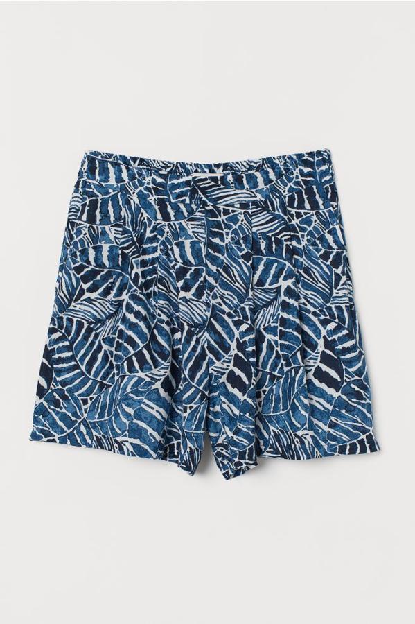 Estampado de hojas azules para estos pantalones cortos de H&M en tejido vaporoso de viscosa con pliegues en el frente para darle un mayor volumen a la prenda. Con perneras amplias, cuestan 9,99 euros y están disponibles entre las tallas 32 y 38, aunque la primera se está agotando.