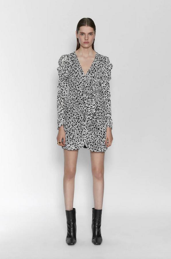 En blanco con manchas negras, este vestido corto con escote de pico cruzado y manga larga abullonada en el hombro es de Zara. Tiene detalle de pliegues y volante en delantero, y cierre cruzado con botones interiores y en lateral. Costaba 29,95 euros y ahora podemos encontrarlo por 15,99 euros entre las tallas XS y XXL.