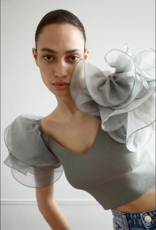 Ideal este top de punto en verde medio con escote pico amplio y manga corta combinada en organza con volumen. Cuesta 19,95 euros.