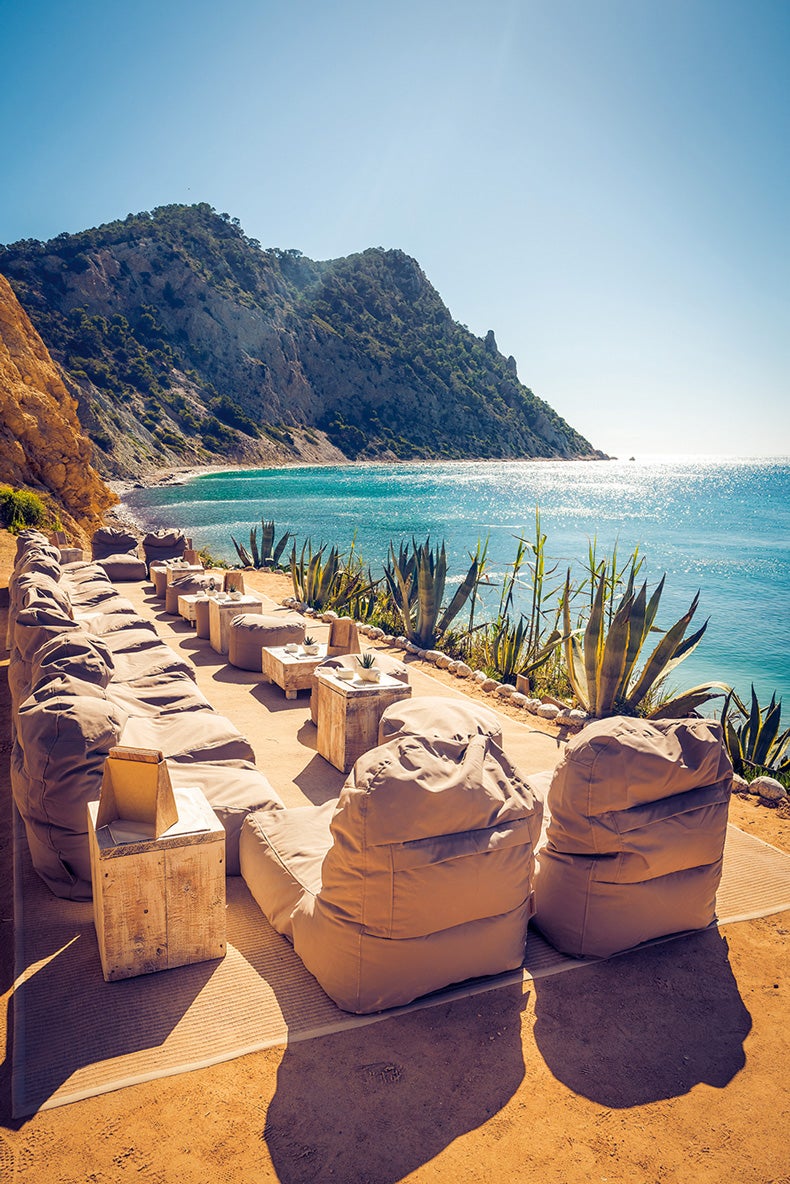 En Cala Llonga, abrazado por un acantilado y con vistas a la bahía de Sol d’en Serra (y en días despejados, a Formentera), este restaurante mediterráneo es un templo a los placeres sencillos, pero rotundos y universales: hamacas, cócteles, una sana carta (fuerte en verduras, carnes y pescados a la brasa en el grill Josper), clases de yoga, cine al aire libre... Abierto día y noche, desde el 3 de julio.