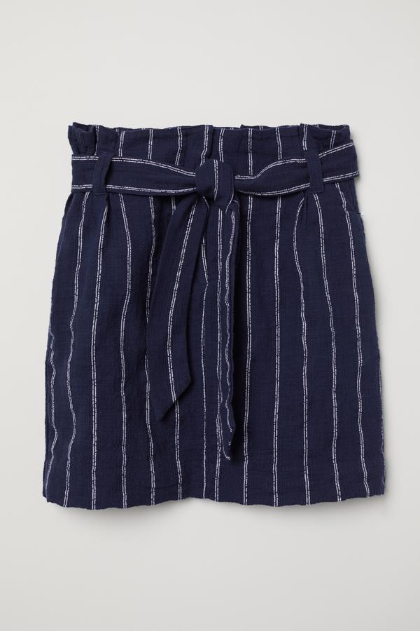 Otra de las propuestas de H&M es esta falda con aires marineros en color azul y rayas verticales blancas confeccionadas en algodón con textura. Con cinturón a tono extraíble y bolsillos ocultos en las costuras laterales, costaba 29,99 euros y ahora podemos encontrarla por 12,99 euros en las tallas 34 y 36, aunque la primera se está agotando.