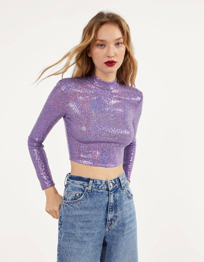 En manga larga y diseño cropped, esta camiseta de Bershka en el color tendencia del año, el lila, viene con brillantes espejitos en toda la prenda y espalda al aire. Tenía un precio de 19,99 euros y ahora  podemos comprarla por 12,99 euros  entre las tallas XS y L.