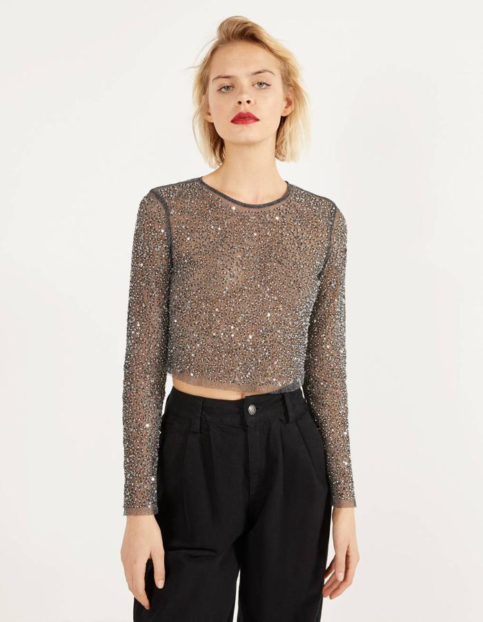 Para las más atrevidas Bershka ha lanzado esta camiseta transparente con abalorios plateados y mangas largas. De 19,99 euros ha pasado  a costar 12,99 euros  y está disponible en las tallas XS y L, aunque la última se está agotando.