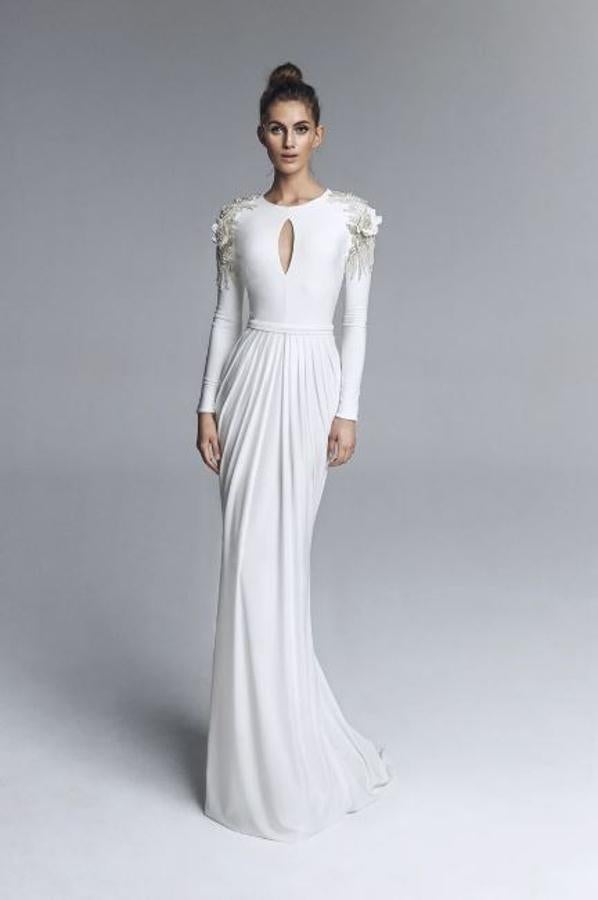 Vestido de novia de punto de seda con corte en cintura y escote a la caja con lágrima. Manga larga con detalle de pedrería sobre los hombros y espalda cerrada. Falda drapeada. Rebajado de 1.390 a 556 euros.