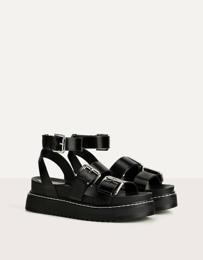 Unas sandalias con una presencia importante que apuestan por el color negro, las grandes hebillas y una plataforma considerable. Comodidad, potencial y estilo (Bershka, 35,99 euros).