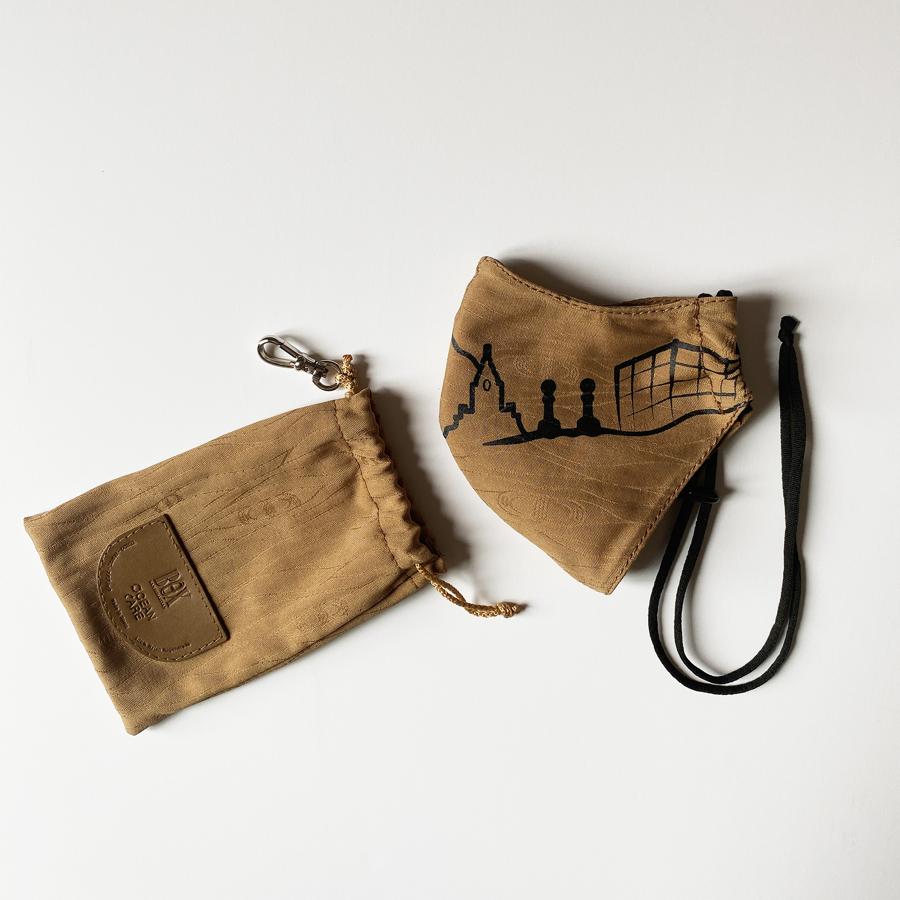 La firma de marroquinería Box San Sebastián ha creado esta mascarilla recordando a la ciudad que les vio nacer. La línea del horizonte donostiarra que han diseñado, va dibujada sobre la mascarilla y se puede elegir entre el dibujo negro o blanco. Va protegida en una bolsa para guardarla junto a los filtros y colgarla desde su mosquetón en tu bolso. Su textil es sostenible y su goma es de látex y ajustable a la cabeza para mayor sujeción y confort. Incluye un segundo filtro de repuesto.