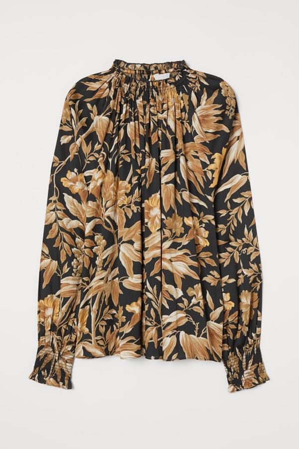 Estampado de flores en color dorado sobre fondo negro para esta blusa de H&M con cuello fruncido y ribete de volante en los puños. Tiene un precio de 19,99 euros y está disponible en las tallas 32, 34 y 36.