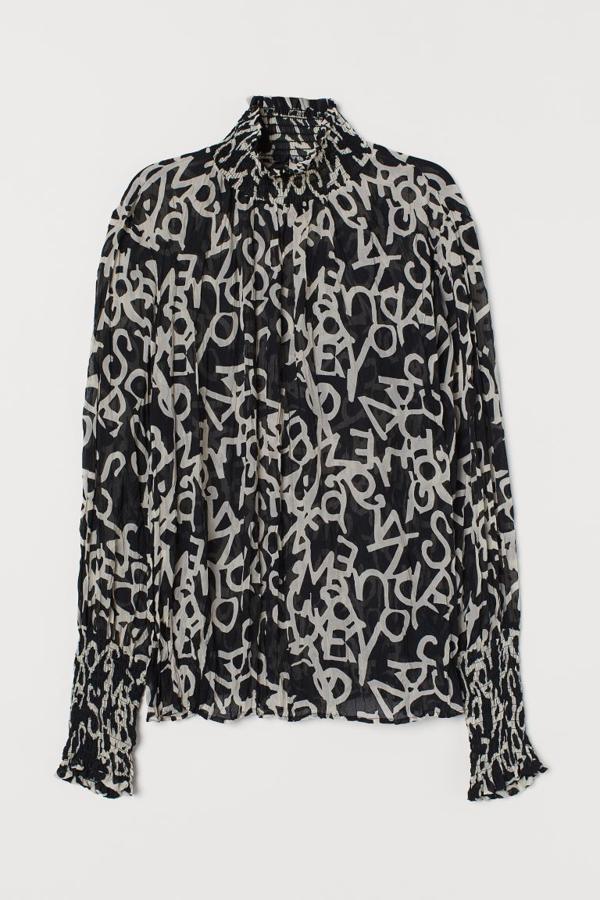 Con un original estampado de letras sobre fondo negro esta blusa de gasa de H&M viene con cuello y puños fruncidos. Cuesta 34,99 euros y está disponible entre las tallas 32 y 40.