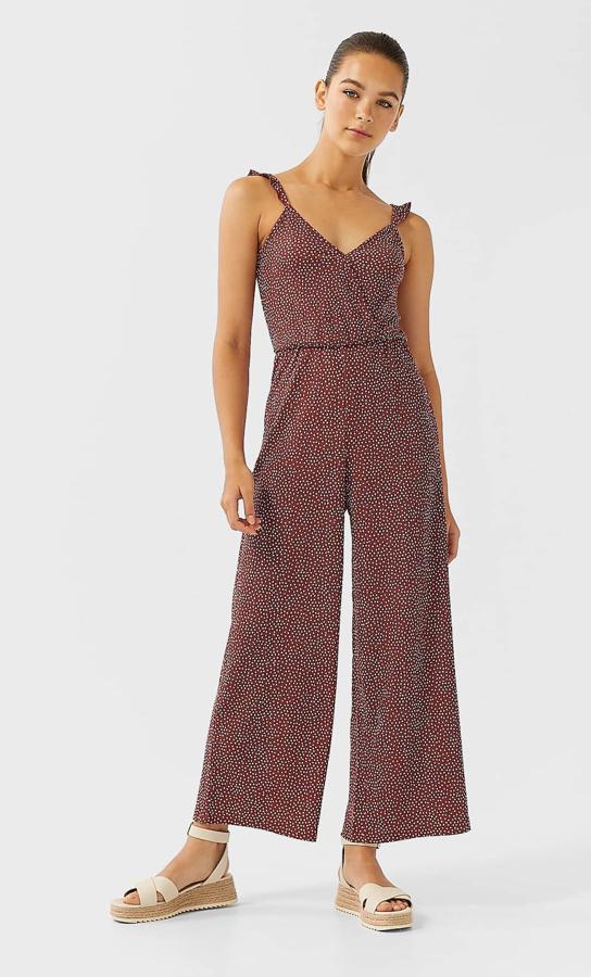 En color camel oscuro (también disponible en negro) y con pequeños topos blancos, este mono largo de tirantes con volante tiene un precio de 19,99 euros.