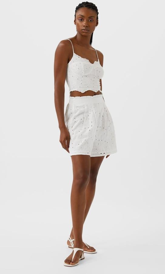 Este crop top en color blanco con escote de pico y tirantes finos ajustables cuenta con detalle de bordado suizo y tiene un precio de 15,99 euros. Tienes el short de tiro alto a juego, con un precio de 17,99 euros.