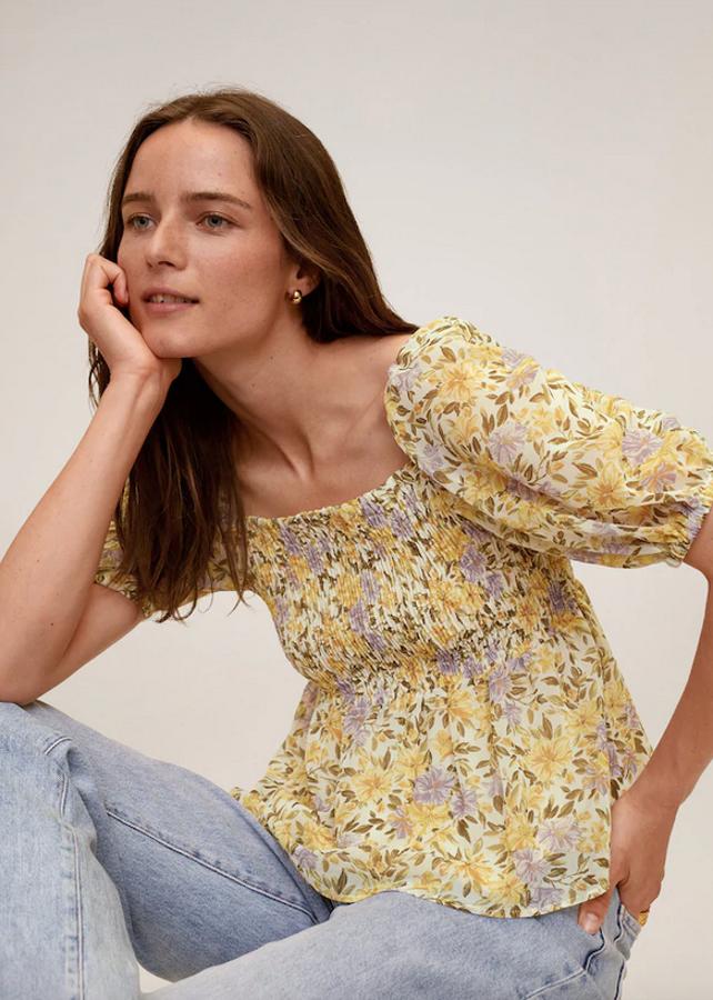 Con cuerpo elástico y manga corta abullonada, esta blusa de Mango en tonos amarillos y violetas viene con cuello recto y cuesta 29,99 euros. Está disponible entre las tallas XS y XL.