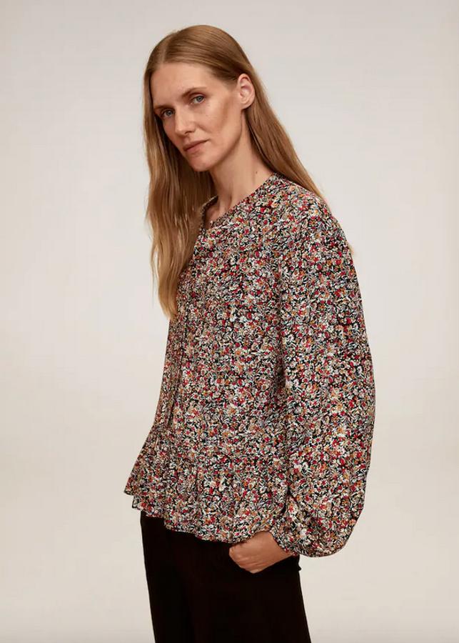 En Mango hemos encontrado esta bonita blusa de tejido fluido y cuello redondo con estampado floral en tonos rojos, negros y marrones. Con manga larga con puños elásticos y detalle de volante en la parte posterior, cuesta 19,99 euros y está disponible entre las tallas XS y XL.