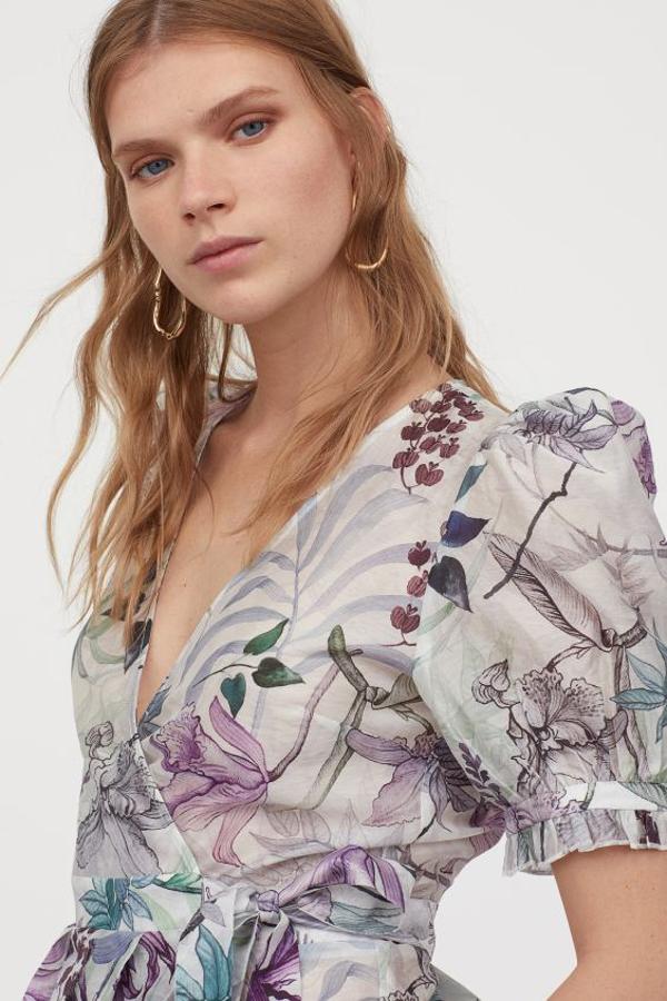 Confeccionada en mezcla de lyocell sostenible, esta bonita blusa de H&M viene con escote de pico pronunciado, frente cruzado con lazada en un lateral y peplo de pliegues. Con mangas cortas abullonadas y en tonos lilas y azulados, solo se vende en la web de la firma y cuesta 34,99 euros. Está disponible entre las tallas 32 y 46.