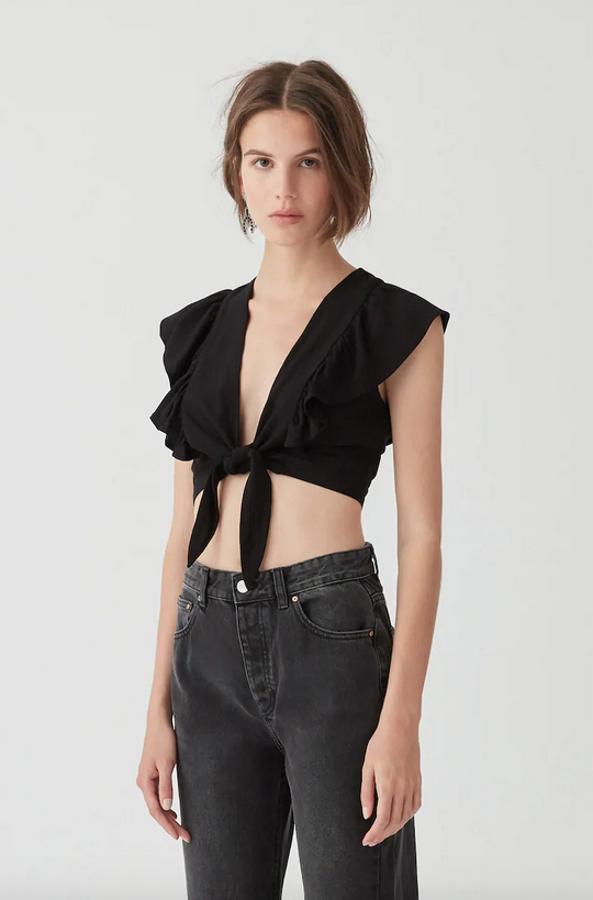 Diseño cropped con volantes y detalle de nudo delantero, este top con manga sisa y escote de pico es de Pull&Bear y cuesta 15,99 euros. Está disponible entre las tallas XS y L.