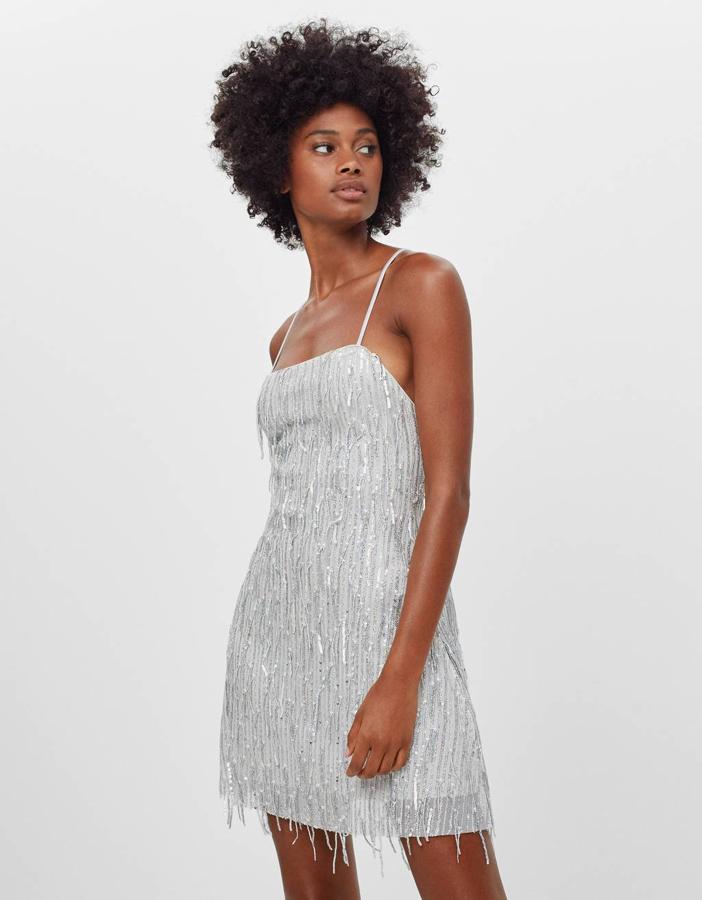 No hay fiesta sin flecos, y en este vestido de Bershka en color plata están muy presentes, y adornados con lentejuelas. Cuesta 29,99 euros y está disponible entre las tallas XS y L.