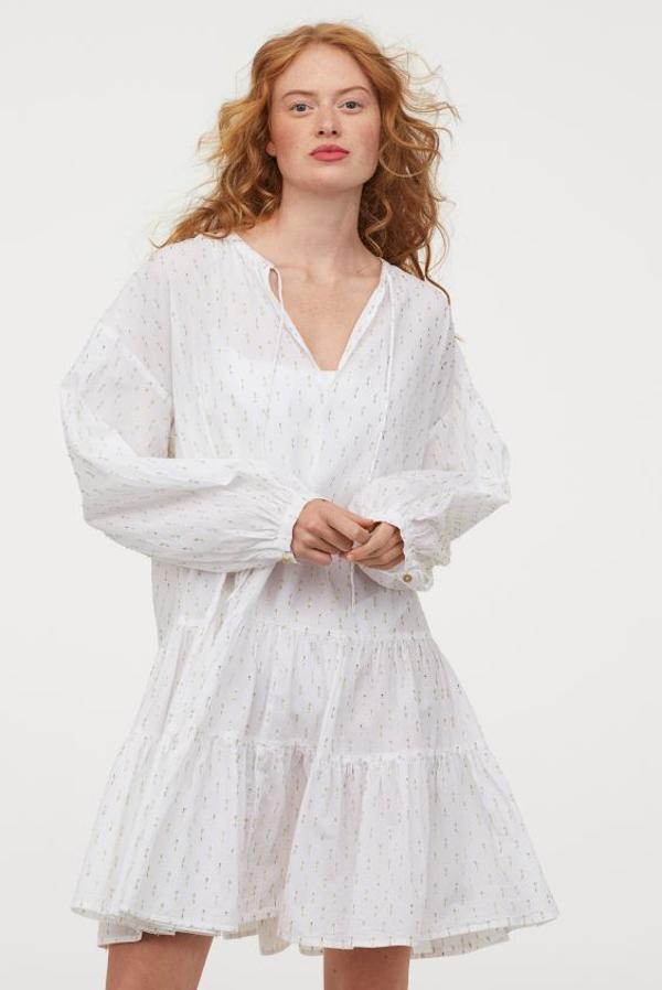 Este vestido de algodón vaporoso con hilos brillantes en la trama es tan bonito que si no lo utilizas únicamente para ir a la playa no pasa nada. Con cuello redondo, abertura en V con lazada, hombros caídos y mangas globos largas con puños sencillos finos, solo está disponible en la web de H&M por 39,99 euros. Y podemos encontrarla entre las tallas XS y L.