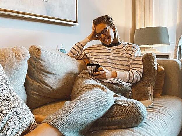 En color gris, el salón cuenta con un gran sofá decorado con cojines con tonos mostaza.