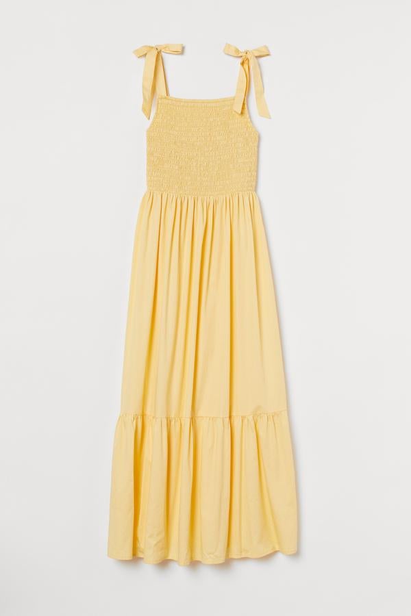 Este vestido midi en algodón vaporoso con cuerpo fruncido cuenta con tirantes anchos con lazo y falda con volumen. En color amarillo, también está disponible en blanco y tiene un precio de 39,99 euros.