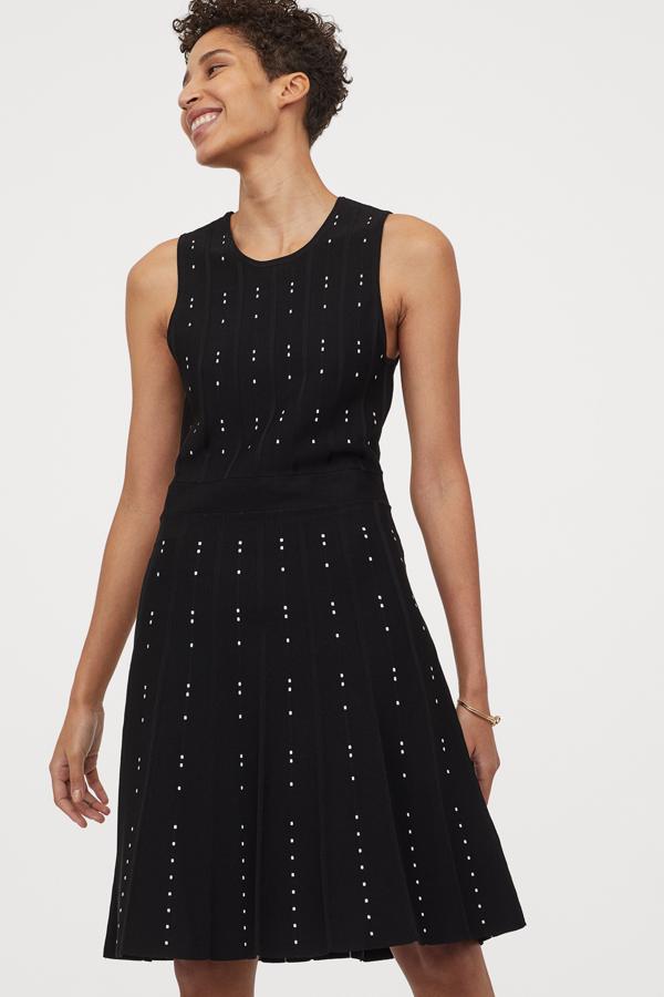 Este vestido sin mangas en punto fino en color negro con pequeños lunares blancos cuenta con falda plisada y cintura entallada. Tiene un precio de 49,99 euros.