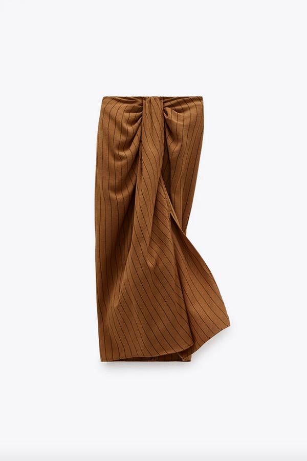 Otra de las propuestas de Zara es esta bonita falda de tiro alto con detalle de nudo y pliegues en delantero en color tostado. Con bajo con abertura frontal, cuesta 29,95 euros y está disponible entre las tallas XS y XXL.