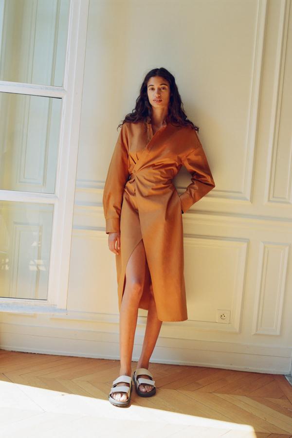 Vestido midi de algodón orgánico con cuello redondo y escote pico, manga larga acabada en puño con pliegues, bolsillos laterales ocultos, cintura con elástico en la espalday cierre cruzado con botón interior y botón lateral, de Zara (29,95 €).