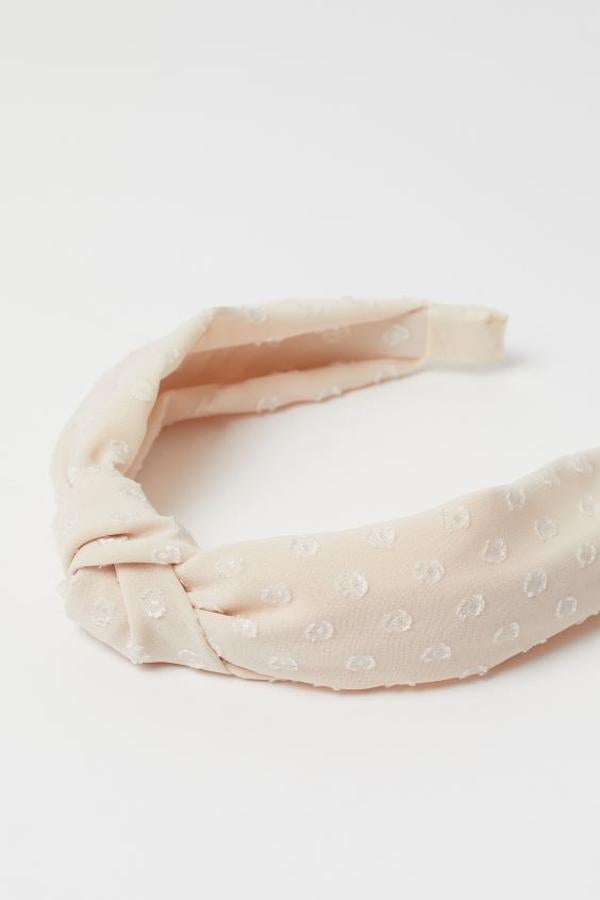 Esta bonita diadema en color beige y plumeti viene con nudo decorativo en la parte superior y cuesta 7,99 euros. Solo está disponible en la web.