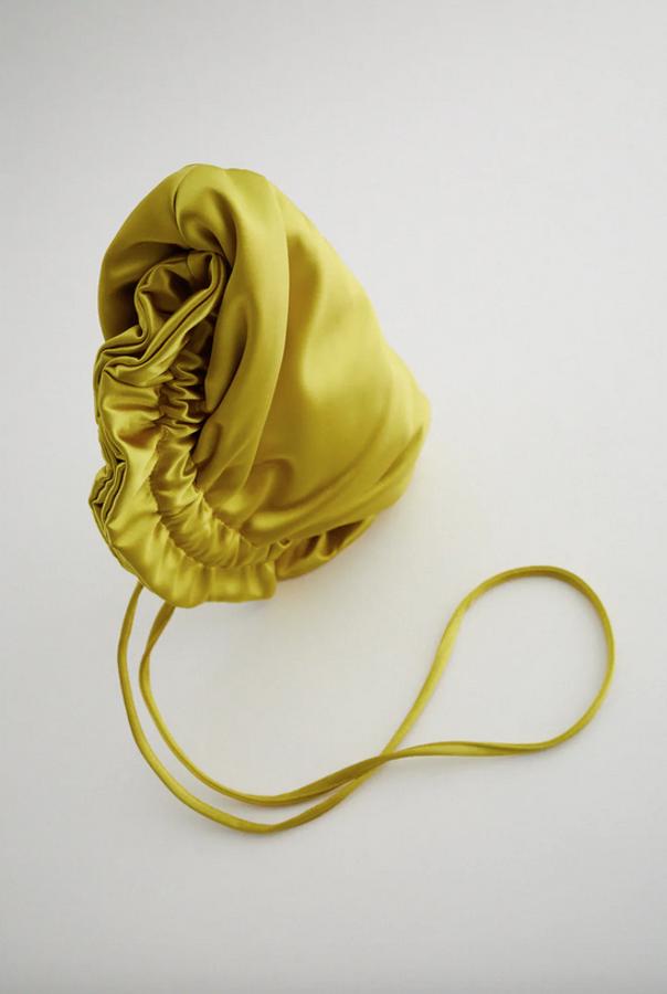 Cuerpo satinado con fruncido en la parte superior para esta bandolera con asa de hombro extraíble e interior forrado con bolsillo y posición para tarjetas. En verde lima o fucsia, cuesta 19,95 euros.