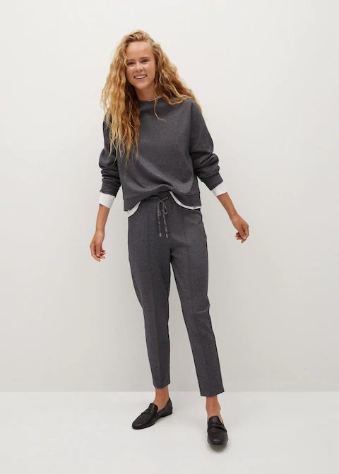 El híbrido ideal: pantalones jaspeados de traje con cierre de cordón ajustable tipo jogger. Combínalos con mocasines, con zapatillas blancas, con sandalias, con botines... (25,99 euros).