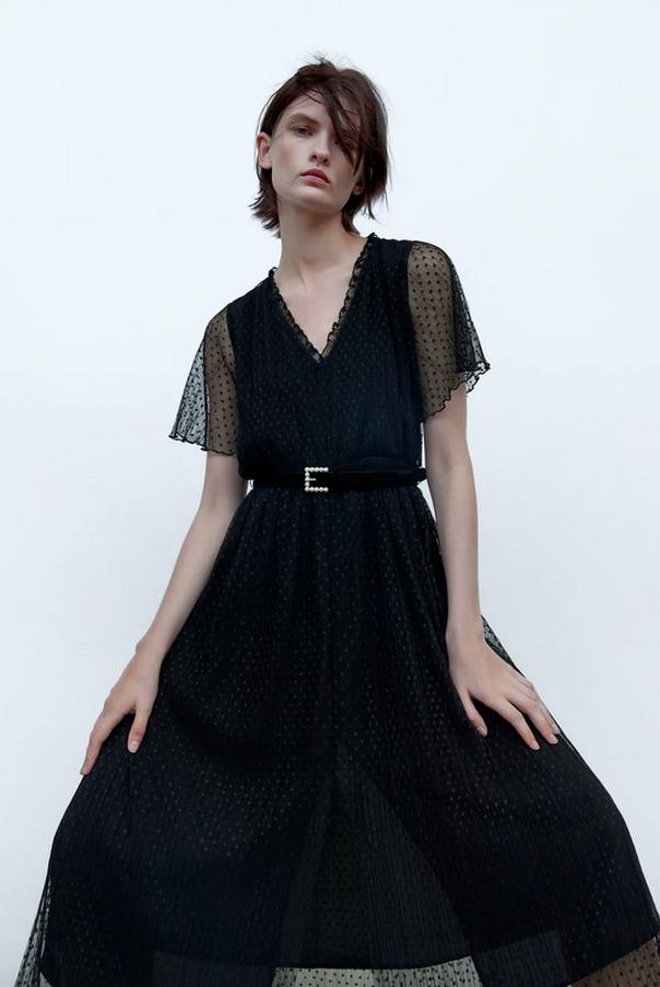 En color negro y plumeti, este vestido midi de Zara viene con escote de pico, mangas cortas y detalle de cinturón con hebilla que tiene aplicación de perlas. Tiene un precio de 39,95 euros y podemos encontrarlo entre las tallas XS y XL.
