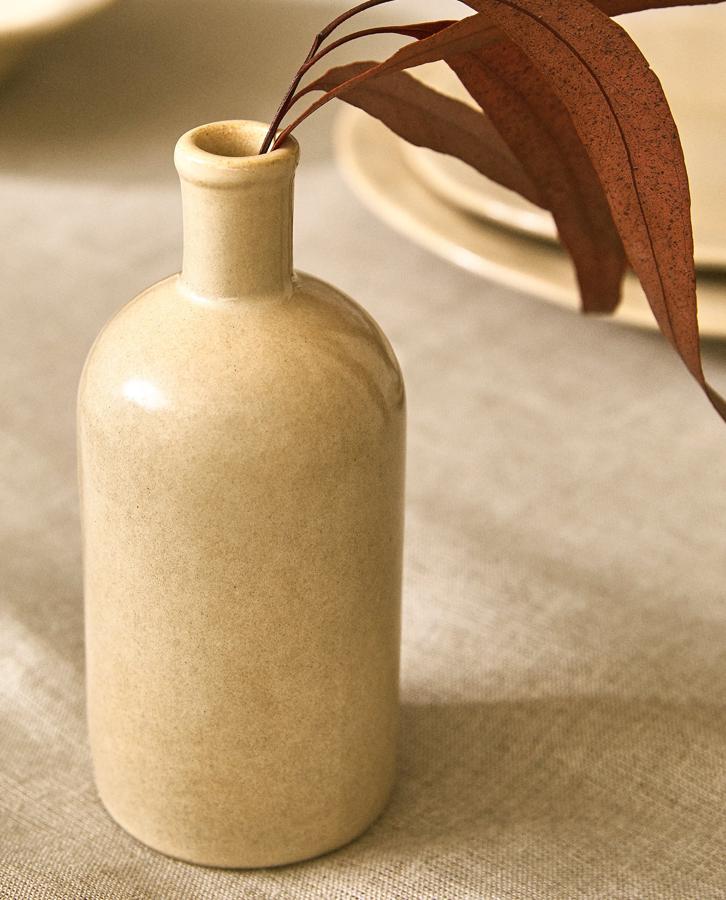 Con forma de botella, este jarrón de gres en color beige puede contener agua y tiene un precio de 12,99 euros.