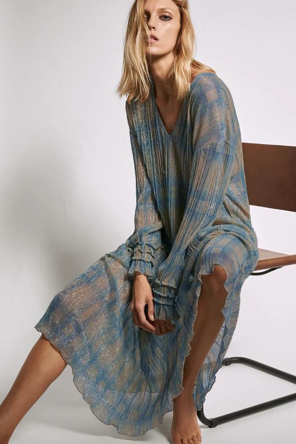 Este vestido semitransparente en color azul acero con escote de pico y manga larga acabada en elástico cuenta con detalle de hilo metalizado y tiene un precio de 19,95 euros.