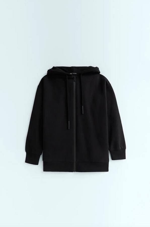 Diseño oversize con cierre de cremallera para esta sudadera negra con capucha ajustable con cordones y bolsillos laterales. Tiene un precio de 25,95 euros y está disponible en las tallas S, M y L.