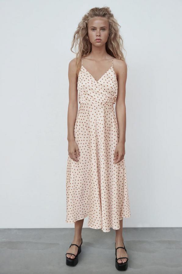 Diseño satinado con escote de pico y tirantes cruzados en la espalda para este vestido de Zara en color crudo con lunares en color café con bajo acabado en evasé tiene un precio de 39,95 euros y está disponible entre las tallas XS y XL.