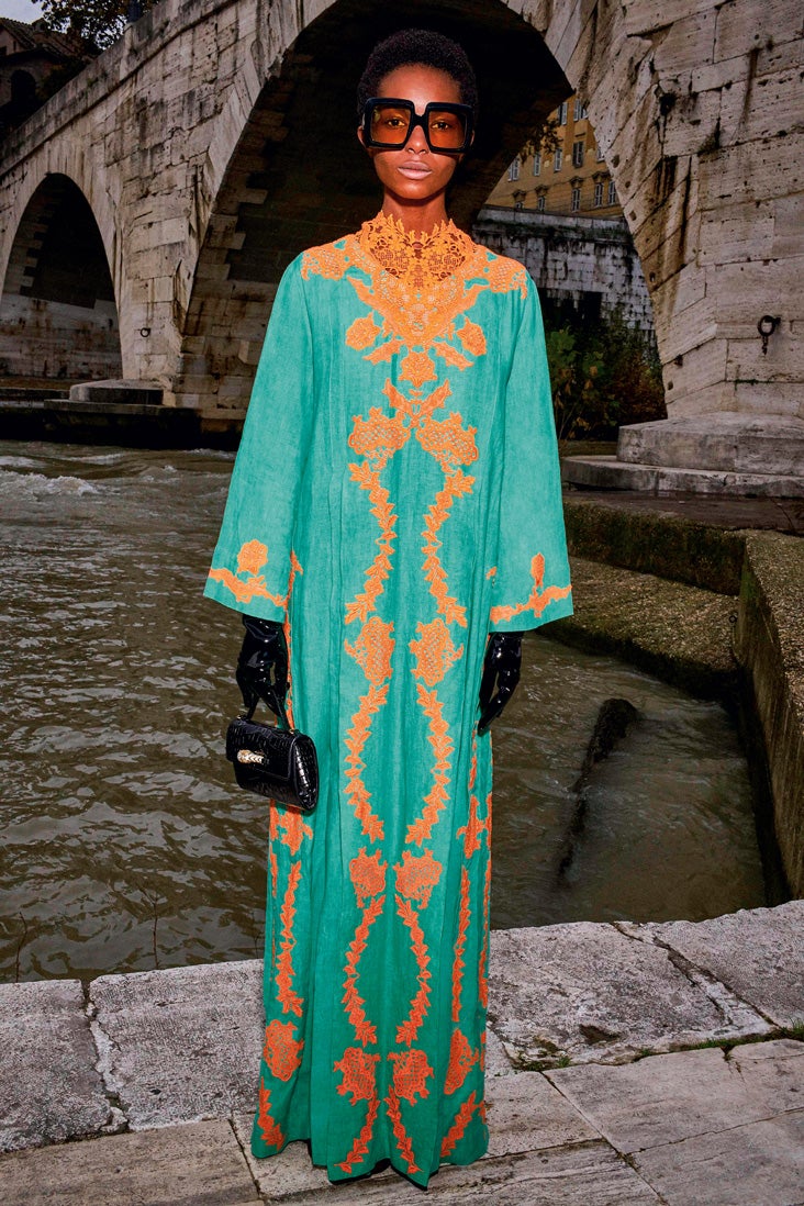 Caftán largo de lino con encaje, gafas de sol, guantes de látex y bolso de mano de cocodrilo, todo de Gucci.