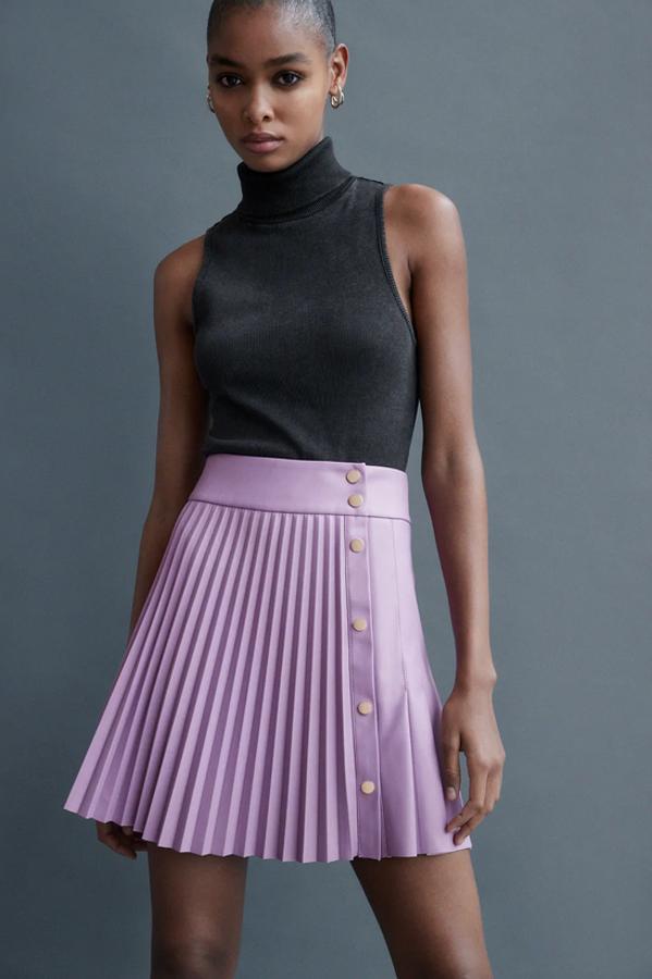 Efecto piel para esta falda mini plisada de Zara en color lila con cierre frontal de botones metálicos a presión en color dorado. Cuesta 25,95 euros y está disponible entre las tallas XS y XL.