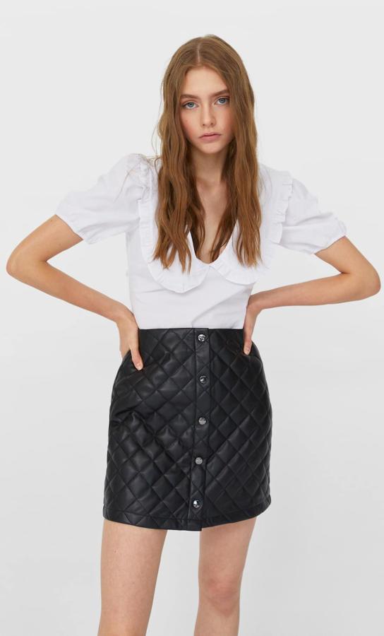En Stradivarius hemos encontrado esta falda mini en efecto piel con diseño acolchado y cierre frontal con botones a contraste. Cuesta 19,99 euros y está disponible entre las tallas 32 y 44.