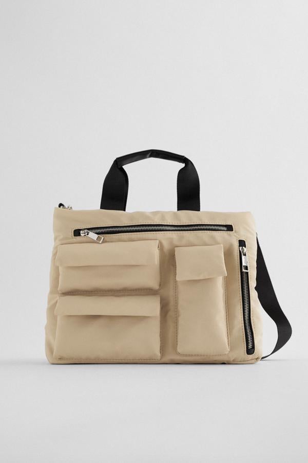Una de nuestras propuestas favoritas es este bolso formato shopper en color beige de Zara con cinco bolsillos en el frontal y asas de hombro y de mano. Tiene un precio de 29,95 euros.